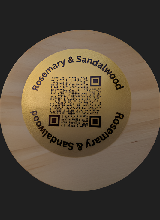 Round wooden candle lid with 'Rosemary & Sandalwood' branding and QR code on a dark background